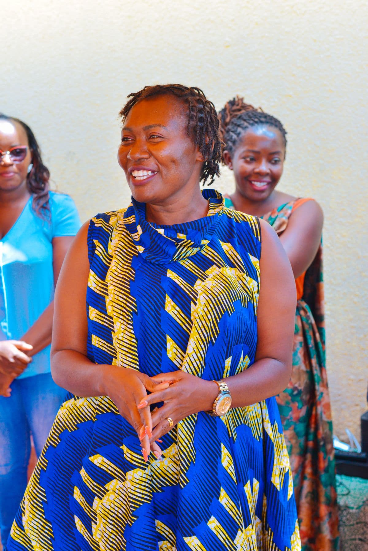 Kenyan women in vibrant traditional dress gathered together, smiling