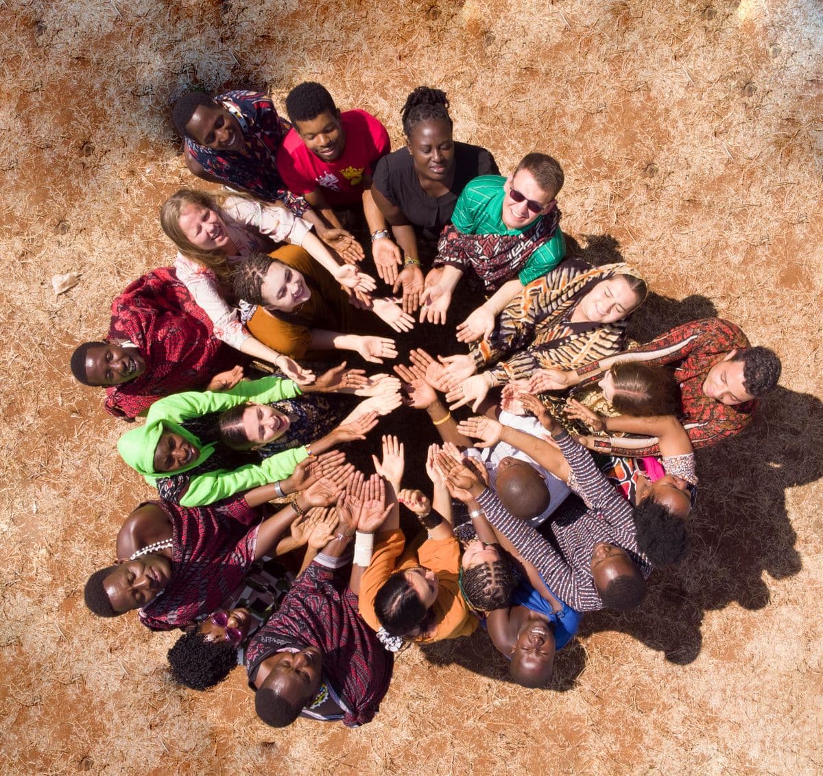 A diverse group standing in a circle with hands joined together, seen from above